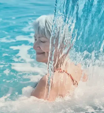 Señora relajada bajo cascada de agua termal